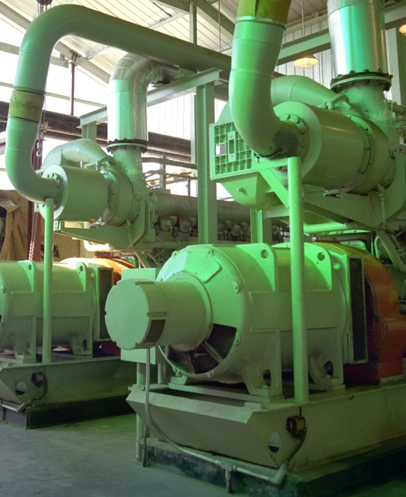 Industrial compressor station equipment with large pipes and machinery.